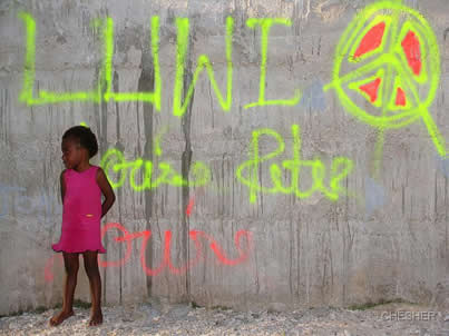 Dark skinned girl from Lelepa standing in front of a wall with graffiti