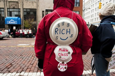 Person wearing red jacket seen from back wearing three paper plates of diminishing sizes labled Rich, Middle Class, and Poor