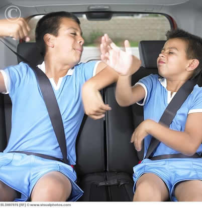 two boys dressed the same fighting in the back seat of a car