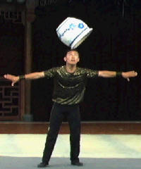Man balancing large pot, upside down on it's rim, on his head